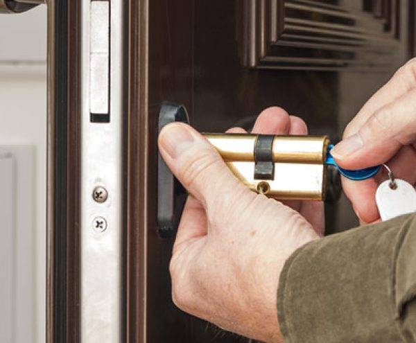 Locksmith services expert installs new lock cylinder on door