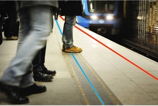 People stand in tube platform waiting for train