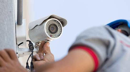 Engineer installs CCTV security system outside office building