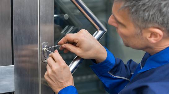 Locksmith services expert fixing lock cylinder in office building main entrance door